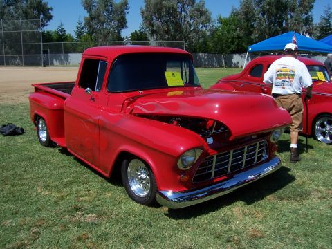 2002 Ford Mustang - A classic red pickup truck with custom flame paint is displayed at an outdoor event.