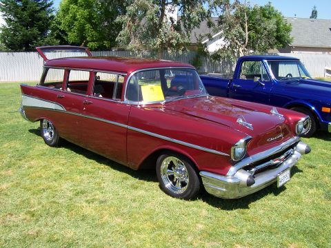 2002 Ford Mustang - A classic red Chevrolet Nomad station wagon is parked on a grassy lawn next to a blue pickup truck.