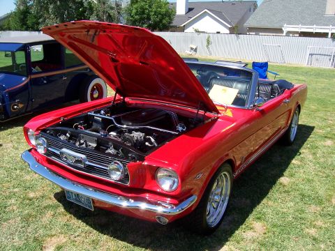 2002 Ford Mustang - A red 1965 Ford Mustang convertible is displayed with its hood open, parked next to another classic vehicle.