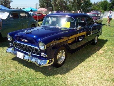 2002 Ford Mustang - A dark blue 1955 Chevrolet Bel Air sedan is parked on a grassy field at an outdoor event.