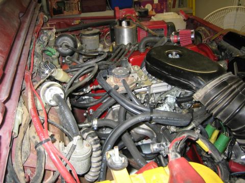 1987 Suzuki Samurai - Close-up view of the engine bay, showing the carburetor, air intake, and various hoses and wiring.