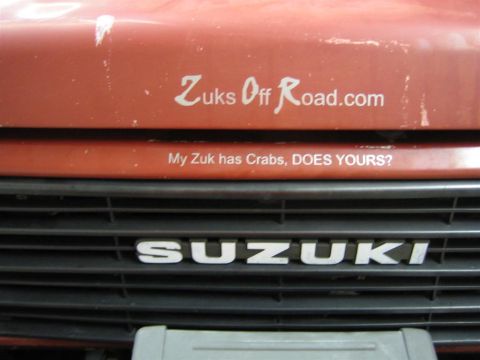 1987 Suzuki Samurai - Close-up of a Suzuki Samurai's front grille and hood, showing "SUZUKI" lettering and decals.
