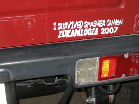 1987 Suzuki Samurai - Sticker on a red vehicle reads 'I SURVIVED SMASHER CANYON ZUKAPALOOZA 2007'.