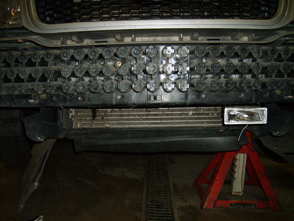 Front bumper area of a vehicle with a grille, radiator, and a fog light being installed