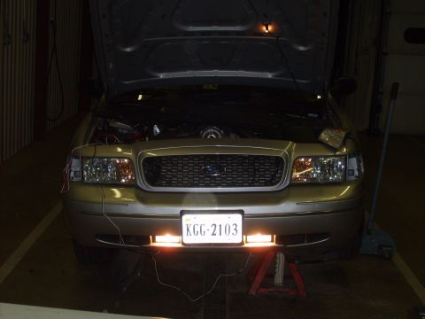 2004 Ford Crown Victoria - Front view of a gold Ford Crown Victoria with its hood open, undergoing modifications.