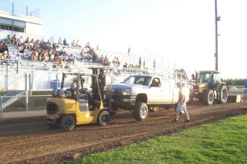 1994 Ford F-150 - A tractor pulls a lifted pickup truck backward, with a forklift assisting the front end.