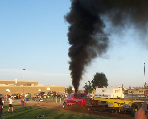1994 Ford F-150 - A red 1994 Ford F-150 participates in a truck pull event, emitting a large cloud of black smoke.