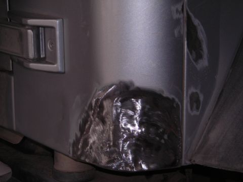 2003 Jeep TJ - Repair work on the rear corner of a 2003 Jeep TJ, showing primer and metal preparation.