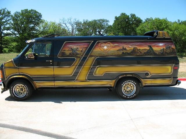 Side view of a black and gold custom van with mural art on the side. It has a heart and landscape painted on it