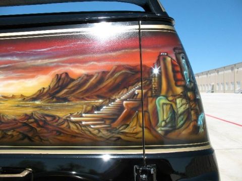 1978 Ford E250 - The side of a van displays a detailed airbrushed mural of a desert landscape with ancient-looking structures.