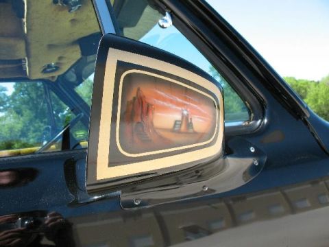 1978 Ford E250 - A custom painted side mirror on a black vehicle displays a desert landscape with a lighthouse at sunset.