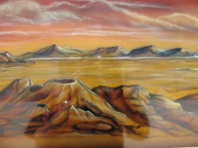airbrushed desert landscape with mountains and a volcano under an orange sky