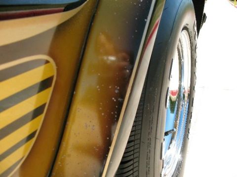 1978 Ford E250 - A close-up side view captures the wheel and striped bodywork of a van.