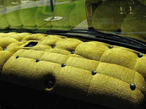 1978 Ford E250 - The dashboard is covered in yellow tufted material with black buttons. A license plate is visible through the windshield.