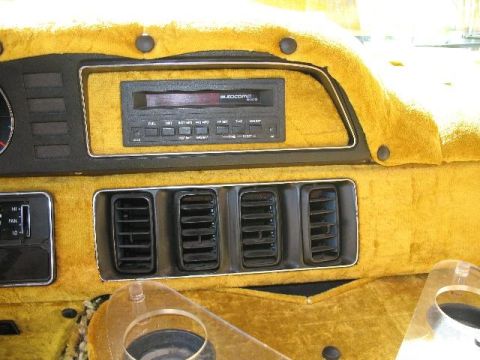 1978 Ford E250 - The dashboard of a van features yellow fuzzy upholstery, an aftermarket radio, and multiple air vents.