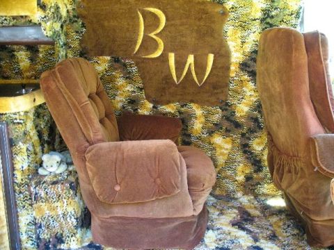 1978 Ford E250 - The interior of a van showcases plush brown seating and distinctive patterned walls, accented by a "BW" emblem.