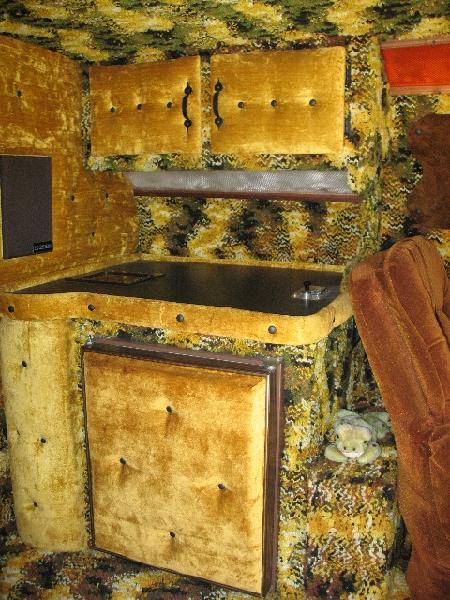 1978 Ford E250 - The interior of a van conversion features extensive yellow velvet upholstery and cabinetry.