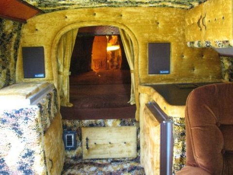 1978 Ford E250 - The interior of a van features plush yellow velvet upholstery, curtains, and speakers, creating a unique living space.