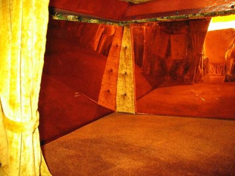 1978 Ford E250 - The interior of a van shows orange carpet and yellow curtains, with red paneling on the walls.