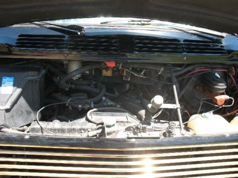 1978 Ford E250 - The engine bay of a black van is shown, with various components and wiring exposed.