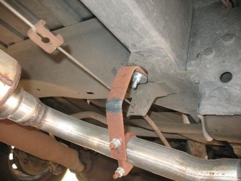 1978 Ford E250 - Underside view of an exhaust system, showing a rusty bracket and clamp holding the pipe.