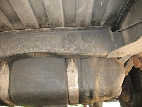 1978 Ford E250 - The underside of a vehicle shows a large fuel tank secured by straps to the frame.
