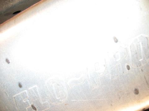 1978 Ford E250 - Close-up of a Flowmaster exhaust muffler, showing embossed branding and mounting points.