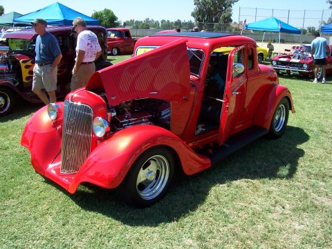 2002 Ford Mustang - A bright red hot rod is displayed with its hood and door open at an outdoor event, its engine and interior.