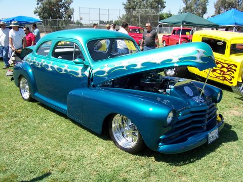 2002 Ford Mustang - A custom hot rod with a two-tone teal and blue paint job flame graphics is displayed with its hood open.