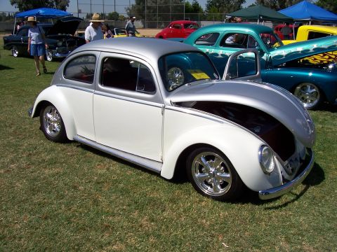 2002 Ford Mustang - Customized Volkswagen Beetle on display at a car show with other classic vehicles.