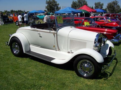 2002 Ford Mustang - A white convertible roadster is parked on grass at a car show with other vehicles in the background.