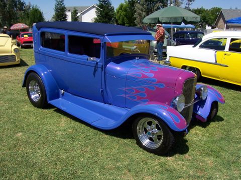 2002 Ford Mustang - A custom blue sedan with flame graphics sits on a grassy field next to other vehicles.