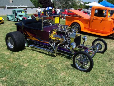 2002 Ford Mustang - A custom hot rod with a powerful engine is displayed at an outdoor car show with other vehicles present.