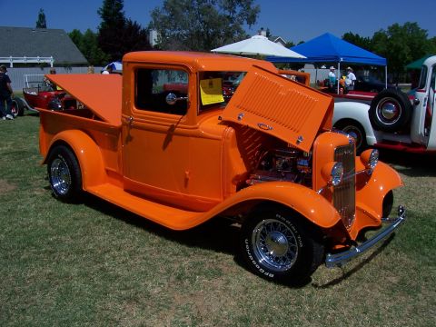 2002 Ford Mustang - An orange vintage pickup truck is displayed with its hood open, the engine bay at an outdoor gathering.