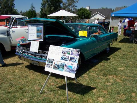2002 Ford Mustang - A teal 1959 Ford Fairlane 500 Skyliner is displayed with its hood open at an outdoor event, alongside a white truck.