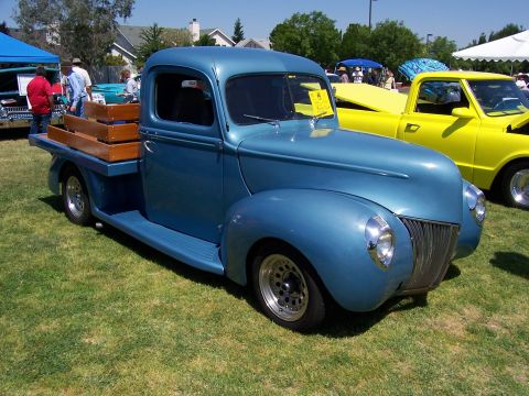 2002 Ford Mustang - A classic blue pickup truck is parked on a grassy lawn next to a yellow pickup truck.