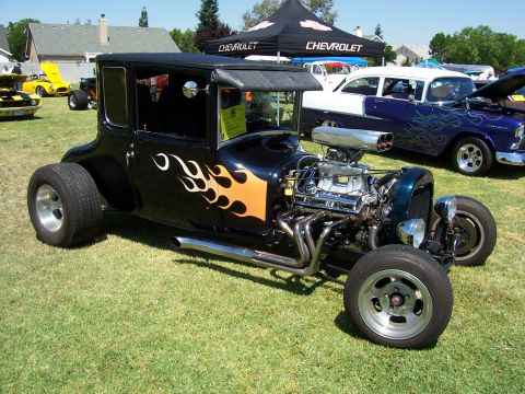 2002 Ford Mustang - A custom hot rod with a powerful engine and flame decals sits on display at an outdoor event.