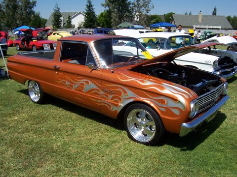 2002 Ford Mustang - A customized 1965 Ford Falcon Ranchero pickup truck with flame graphics is displayed at an outdoor event.