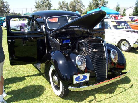 2002 Ford Mustang - A black vintage car is displayed with its hood and driver's door open on a grassy field.