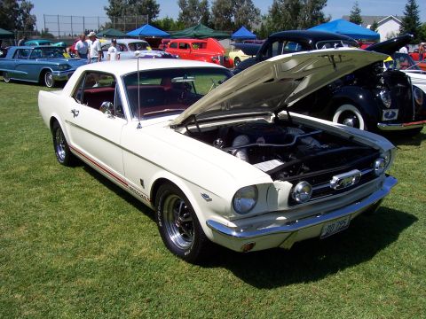 2002 Ford Mustang - This classic white 1965 Ford Mustang coupe is displayed with its hood open, revealing the engine and a glimpse of its red interior.