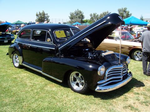 2002 Ford Mustang - A black classic sedan is displayed with its hood open at an outdoor car show.