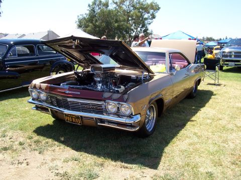 2002 Ford Mustang - A customized classic car with its hood open, revealing a powerful engine, sits on display at an outdoor event.