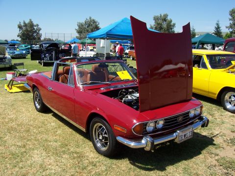 2002 Ford Mustang - A red convertible with its hood open is displayed at an outdoor car show next to a yellow car.