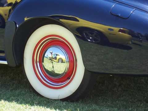 2002 Ford Mustang - Reflection of a yellow car is visible in the hubcap of a dark blue car with whitewall tires.