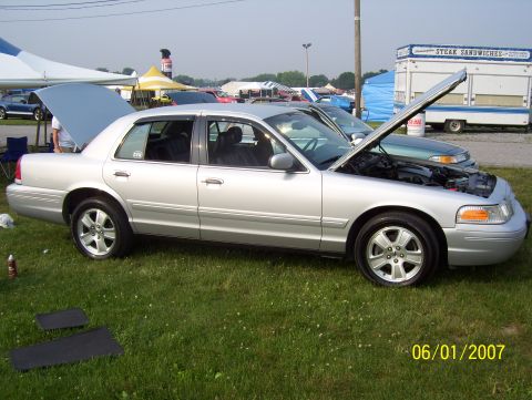 2003 Ford Crown Victoria - A silver 2003 Ford Crown Victoria is displayed with its hood and trunk open at an outdoor event.