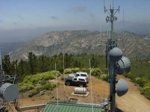 1994 Ford Bronco - Two SUVs are parked on a hilltop, with a large radio tower and a scenic mountain view.