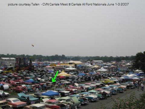 1996 Mercury Grand Marquis - A large gathering of vehicles and people at an outdoor event, with tents set up for vendors or shade.