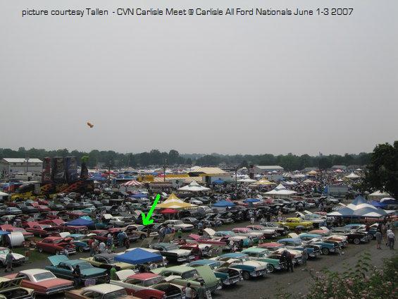 Aerial view of crowded Carlisle car show with tents and a green arrow pointer