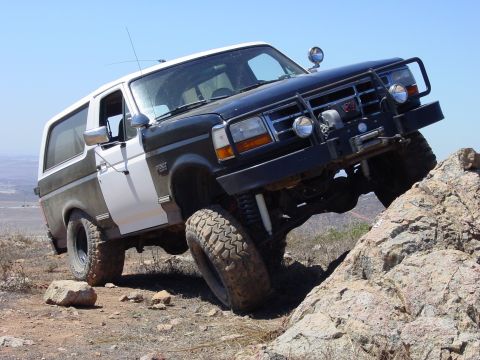 1994 Ford Bronco - Ford Bronco navigating a rocky off-road course under a clear blue sky.