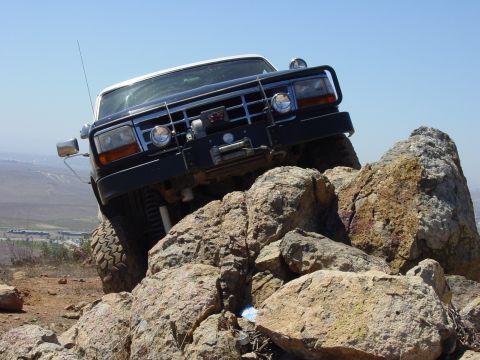 1994 Ford Bronco - This Ford Bronco is navigating a rocky trail under a clear blue sky.